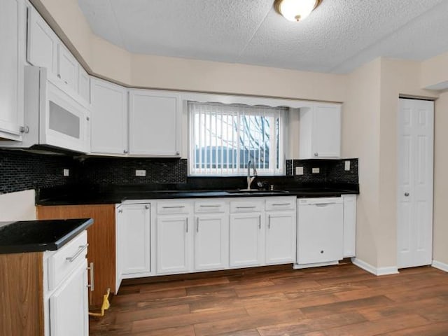 kitchen with sink, white appliances, dark wood-type flooring, a textured ceiling, and white cabinets