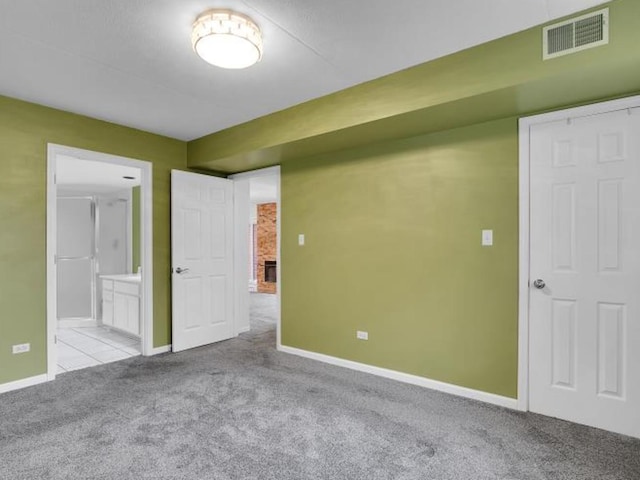 unfurnished bedroom featuring ensuite bathroom and light colored carpet