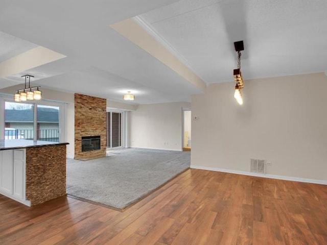 unfurnished living room featuring hardwood / wood-style flooring, ornamental molding, and a fireplace