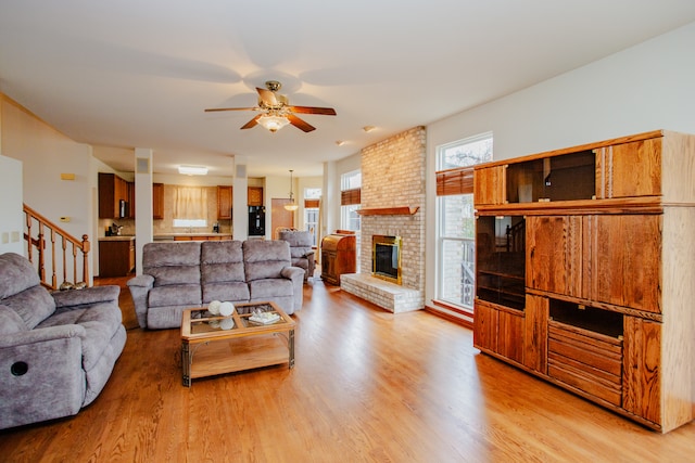 living room with ceiling fan, a fireplace, and light hardwood / wood-style floors