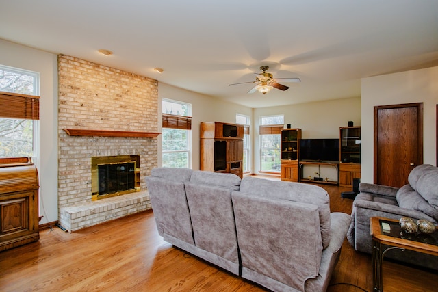 living room with a fireplace, ceiling fan, and light hardwood / wood-style flooring