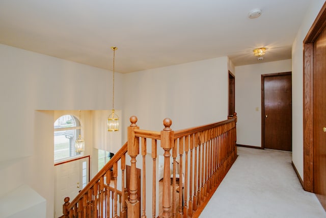 hall with a chandelier and light colored carpet