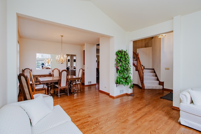 living room with a chandelier, wood-type flooring, and lofted ceiling