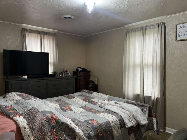 bedroom featuring hardwood / wood-style floors, ornamental molding, a textured ceiling, and multiple windows