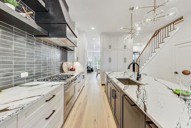 kitchen with hanging light fixtures, light stone counters, light hardwood / wood-style floors, white cabinets, and appliances with stainless steel finishes