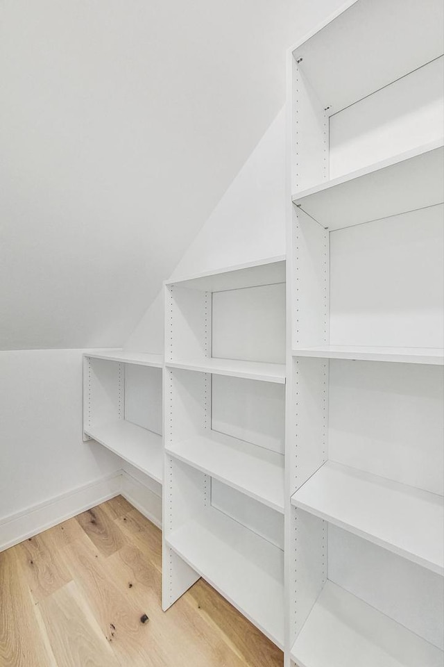 walk in closet with wood-type flooring and vaulted ceiling