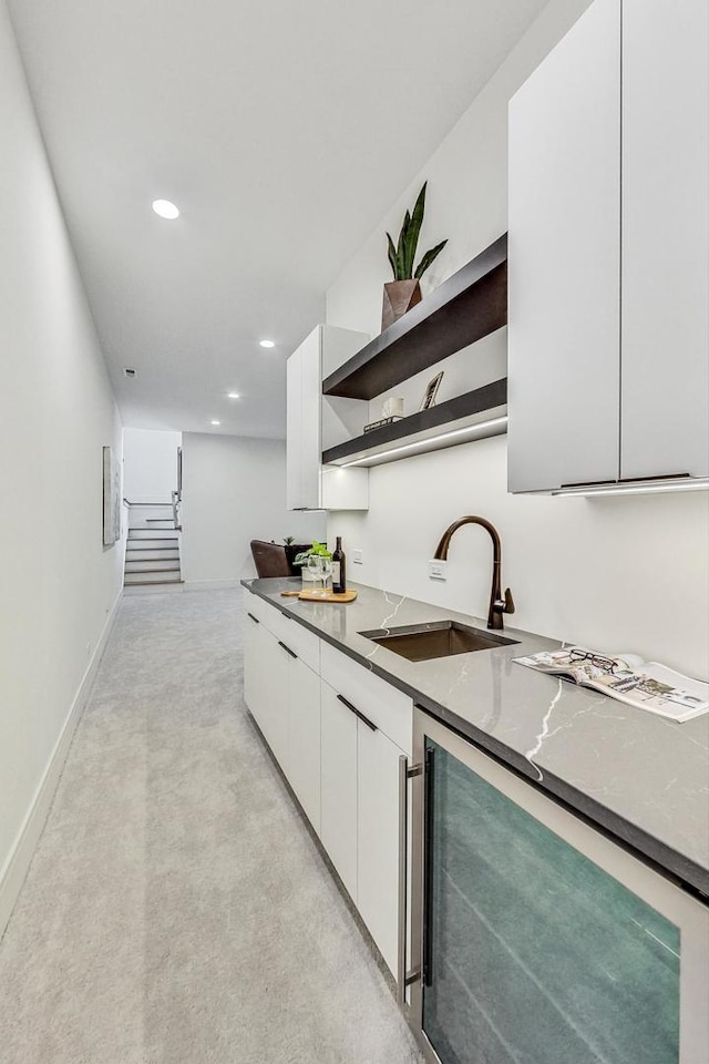 kitchen featuring wine cooler, sink, white cabinets, and stone countertops