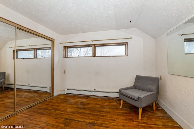 unfurnished room featuring wood-type flooring, lofted ceiling, and a baseboard radiator