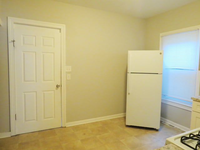 kitchen featuring white refrigerator, white cabinetry, and range