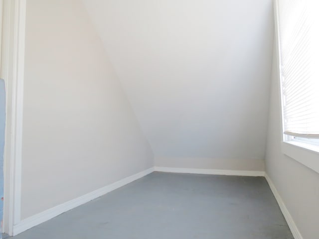 empty room with concrete flooring and vaulted ceiling