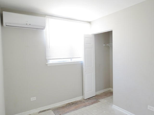 unfurnished bedroom featuring a wall mounted air conditioner and a closet