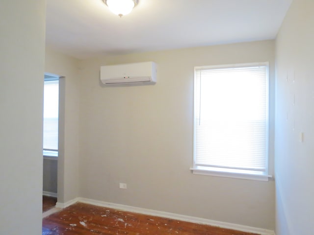 empty room featuring a wall mounted air conditioner and hardwood / wood-style floors