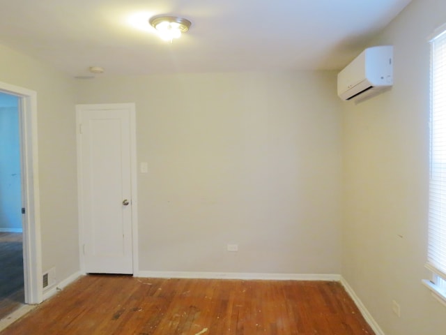 spare room featuring a wall mounted air conditioner and hardwood / wood-style flooring