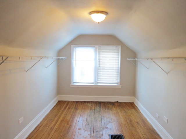 spacious closet with light hardwood / wood-style floors and lofted ceiling