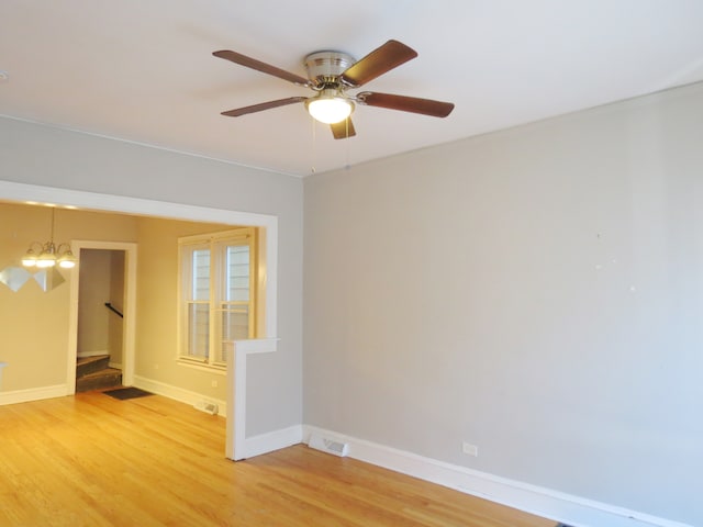 spare room with hardwood / wood-style floors and ceiling fan with notable chandelier