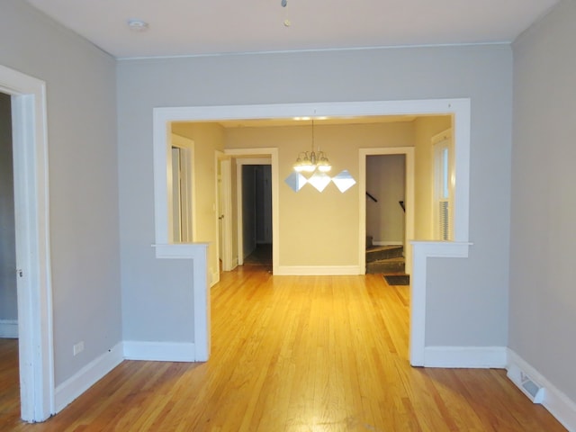 unfurnished dining area featuring a chandelier and light hardwood / wood-style floors