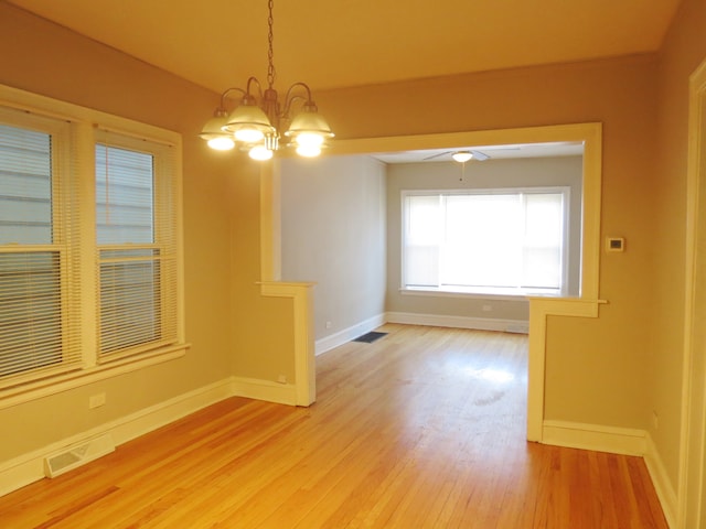 unfurnished room featuring wood-type flooring and ceiling fan with notable chandelier