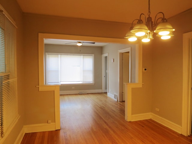 empty room with wood-type flooring and ceiling fan with notable chandelier