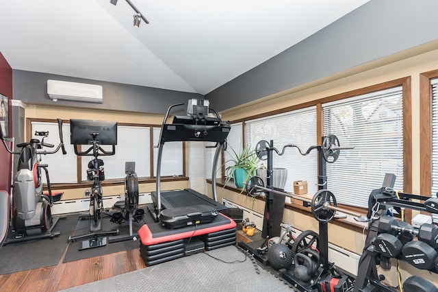 workout area with an AC wall unit, hardwood / wood-style floors, and vaulted ceiling