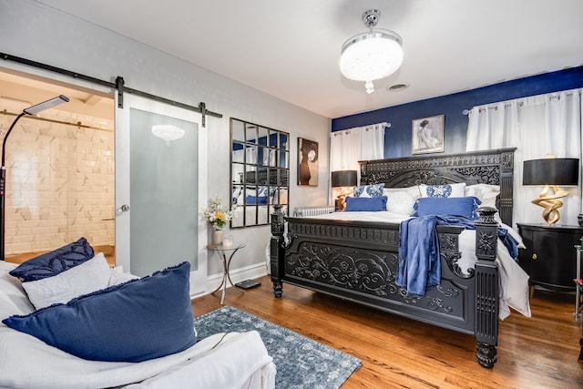 bedroom featuring a barn door and hardwood / wood-style flooring