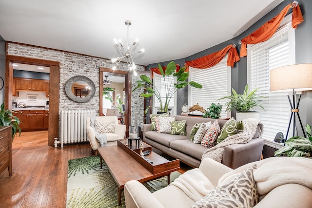 living room featuring brick wall, radiator heating unit, a notable chandelier, and hardwood / wood-style floors