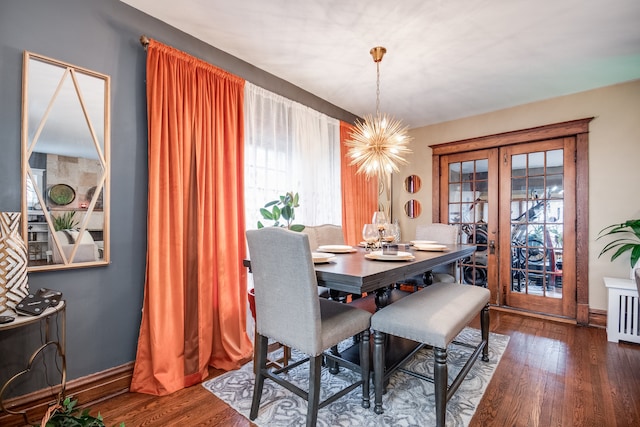 dining area with dark hardwood / wood-style floors, a wealth of natural light, and an inviting chandelier