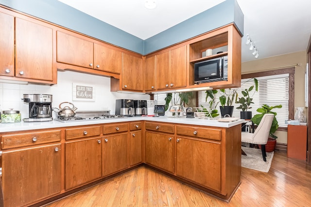 kitchen featuring decorative backsplash, track lighting, light hardwood / wood-style flooring, and stainless steel gas cooktop