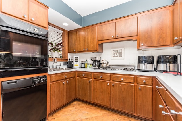 kitchen with black appliances, backsplash, light wood-type flooring, and sink