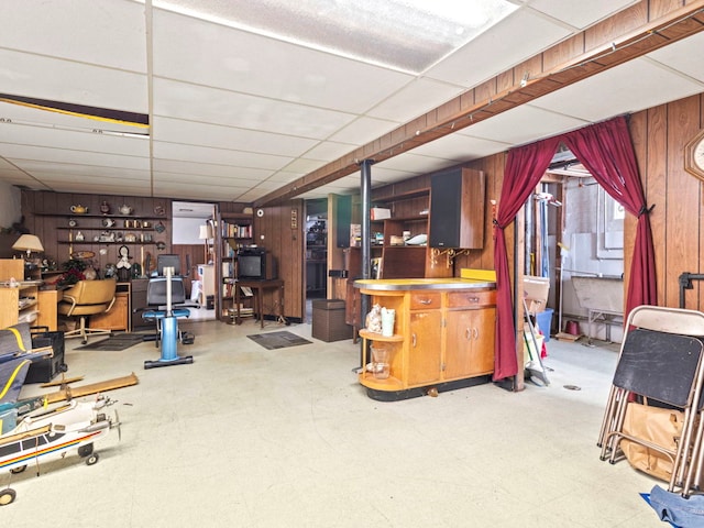 basement featuring a drop ceiling and wooden walls