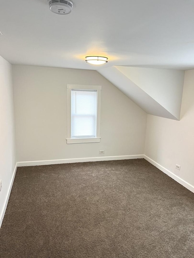 additional living space with dark colored carpet and lofted ceiling