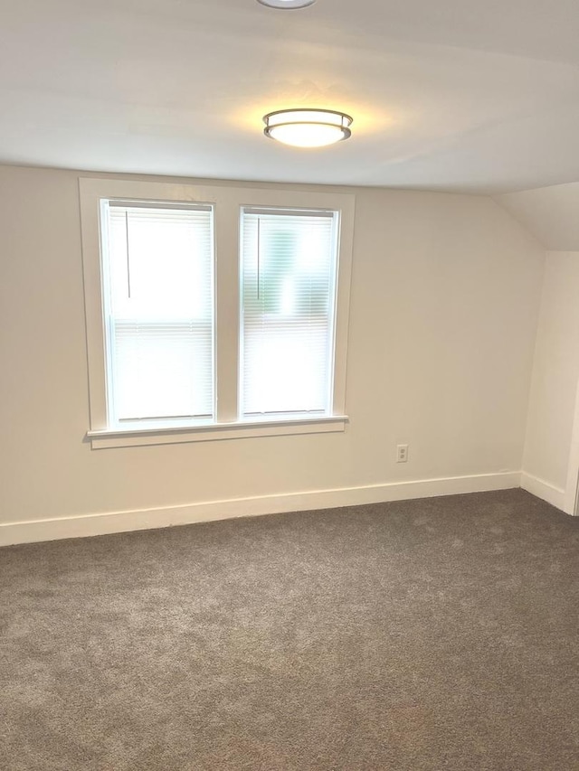 carpeted spare room with lofted ceiling