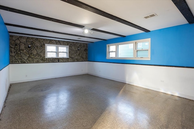 empty room featuring beam ceiling and a healthy amount of sunlight