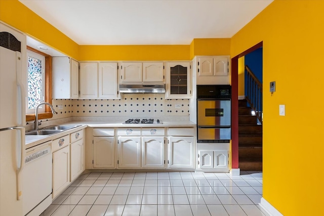 kitchen with backsplash, sink, light tile patterned floors, and white appliances