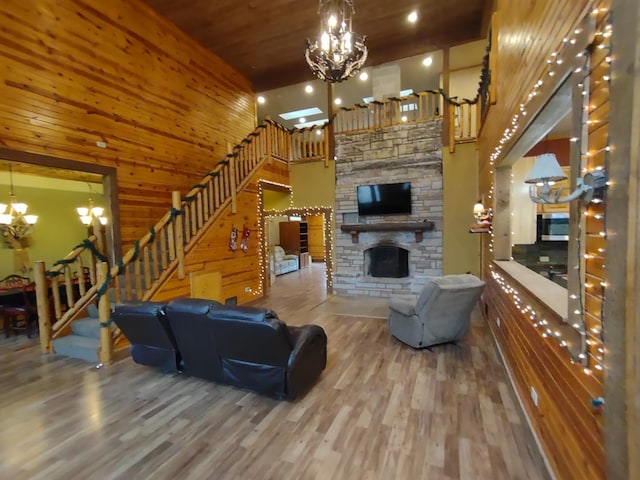 living room with a notable chandelier, hardwood / wood-style floors, a high ceiling, wood ceiling, and a stone fireplace