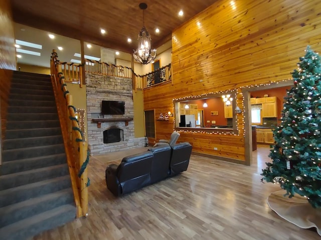 living room with hardwood / wood-style flooring, wood walls, wooden ceiling, a high ceiling, and a fireplace