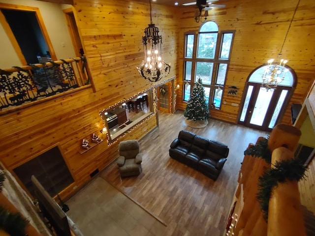 living room featuring a high ceiling, hardwood / wood-style floors, wood walls, and a healthy amount of sunlight