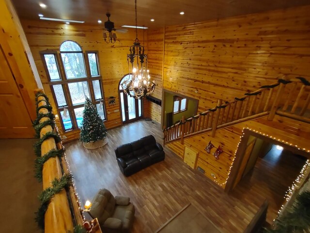 unfurnished living room featuring wood walls, french doors, wood-type flooring, vaulted ceiling, and ceiling fan with notable chandelier