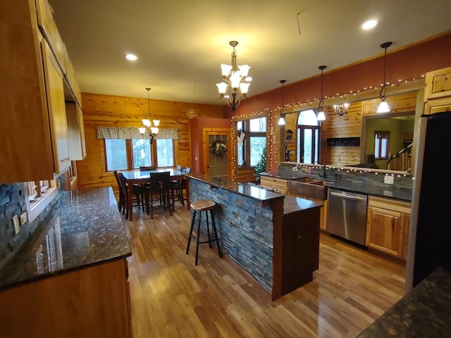 kitchen with stainless steel appliances, hanging light fixtures, a chandelier, light hardwood / wood-style flooring, and a center island