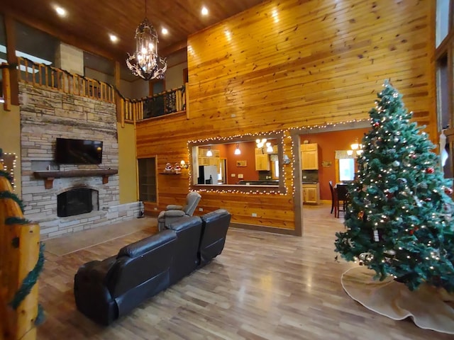 living room featuring a towering ceiling, a stone fireplace, wood walls, hardwood / wood-style flooring, and wooden ceiling