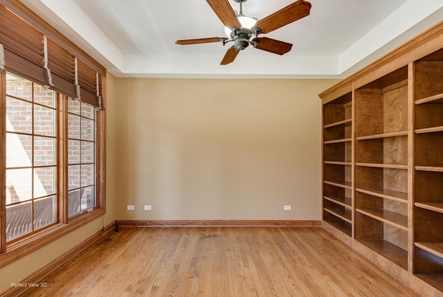 empty room featuring light hardwood / wood-style flooring, a raised ceiling, and ceiling fan