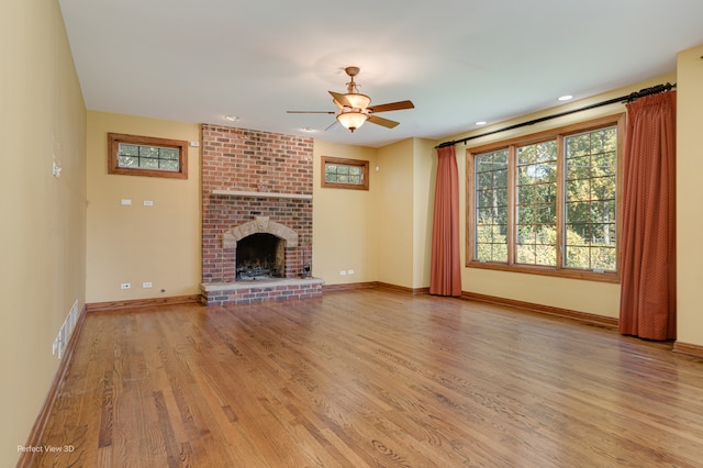 unfurnished living room featuring light hardwood / wood-style floors, a brick fireplace, and ceiling fan