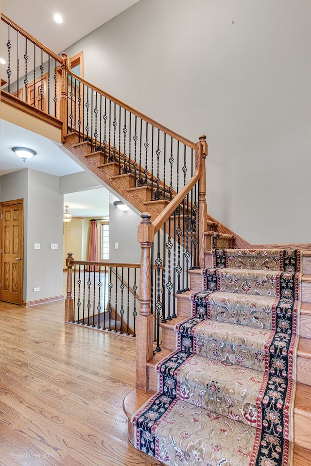 stairway featuring hardwood / wood-style flooring and a towering ceiling