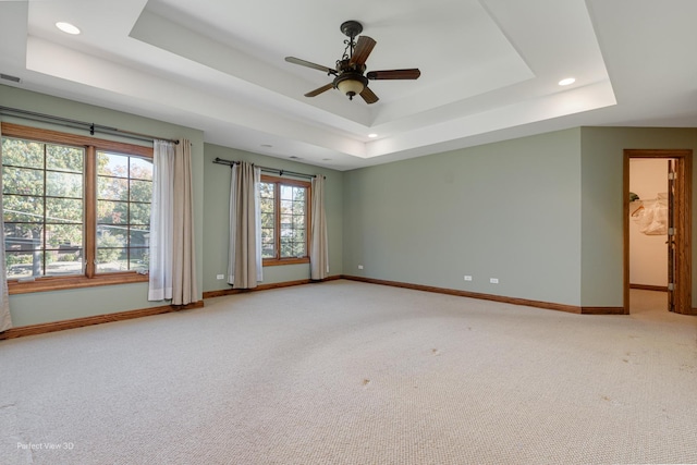 unfurnished room featuring a tray ceiling, carpet floors, and ceiling fan