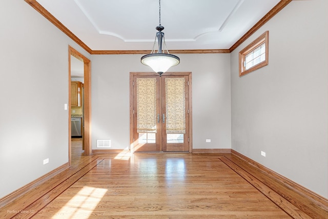 empty room featuring french doors, crown molding, and light hardwood / wood-style floors