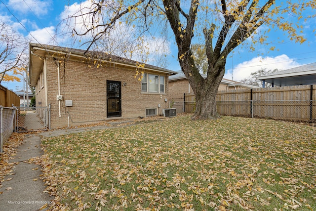 rear view of house with cooling unit and a lawn