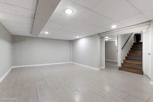 basement featuring a paneled ceiling and light wood-type flooring