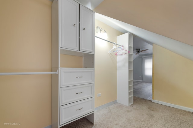 walk in closet with ceiling fan, light carpet, and vaulted ceiling