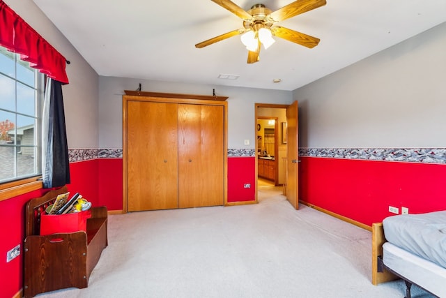 bedroom with ceiling fan, light carpet, and a closet