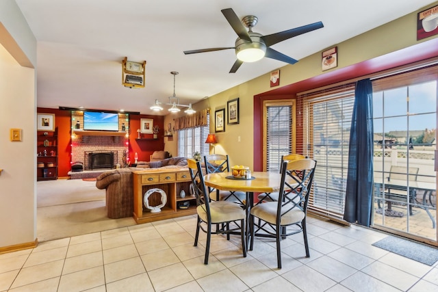 tiled dining space featuring ceiling fan and a brick fireplace