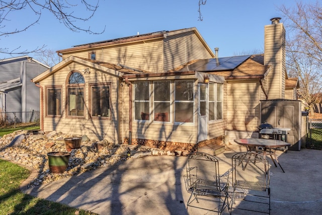 back of property with a sunroom, solar panels, and a patio area